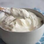 cream cheese frosting without butter is scooped from a grey bowl