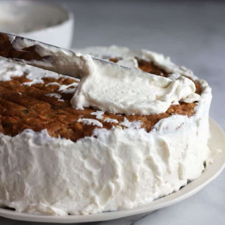 fluffy white frosting being spread over round layer cake