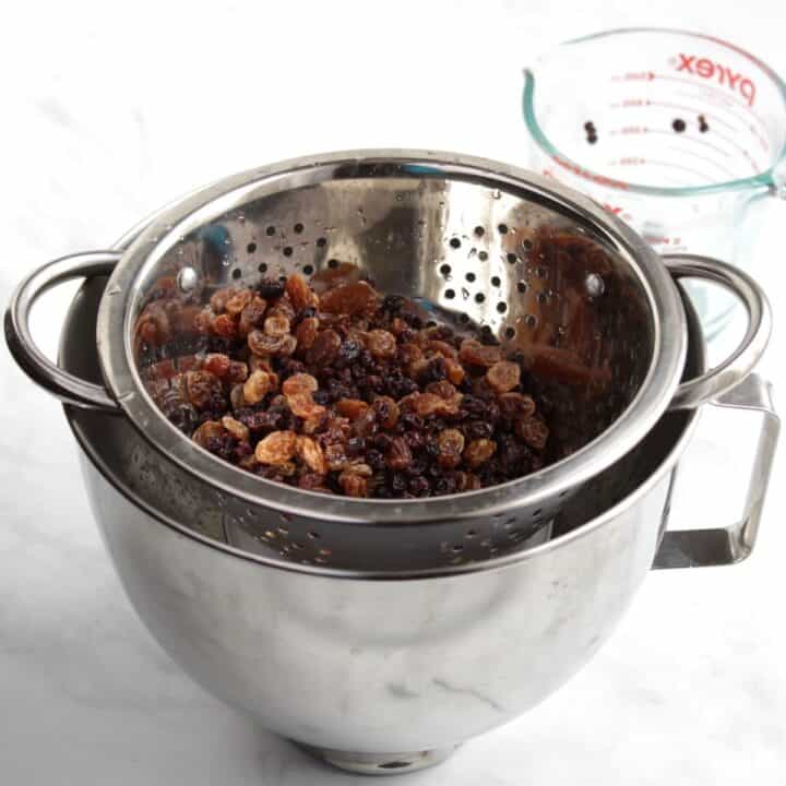 plump raisins and currants in colander over bowl of stand mixer