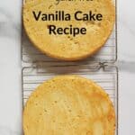 two baked vanilla cake layers cooling on wire racks.