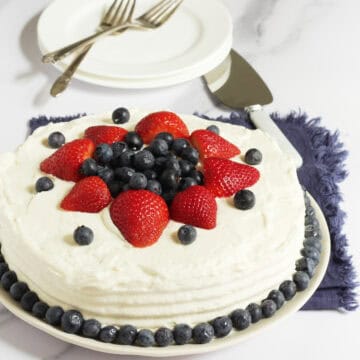 round white layer cake decorated with red and blueberries.