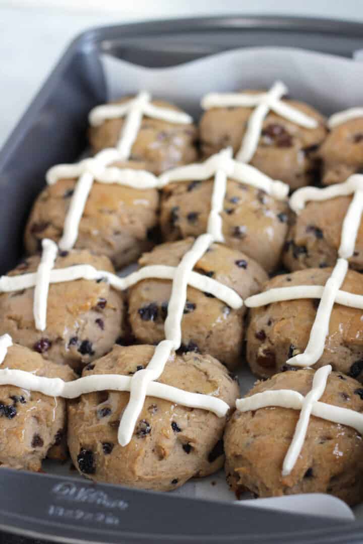 rows of gluten free hot cross buns with iced crossed on them sit in baking pan