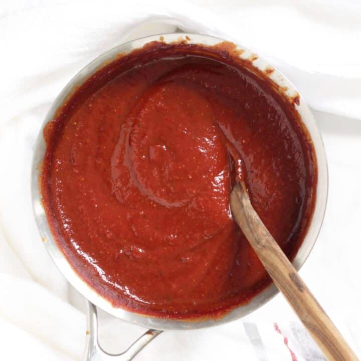 thickened, cooked red barbecue sauce in small saucepan with wooden spoon