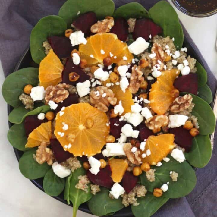 looking down on plate of orange segments, crumbled feta, chunks of roasted beets, and walnuts on fresh spinach - an assembled roast beetroot salad