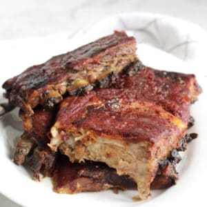 ribs in barbecue sauce piled on white plate