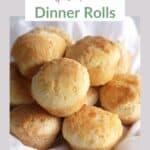 pile of round, golden dinner rolls on white napkin
