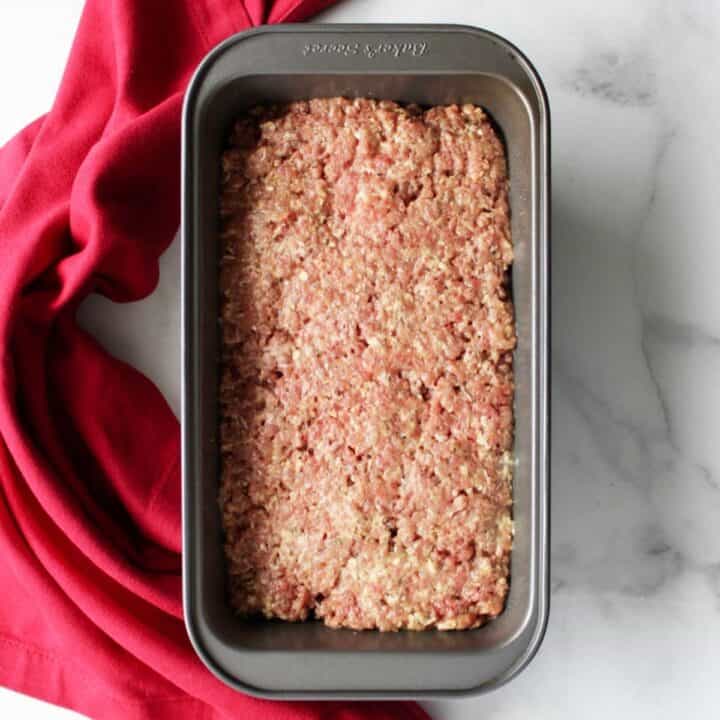 raw ground beef mixture pressed into a metal loaf pan
