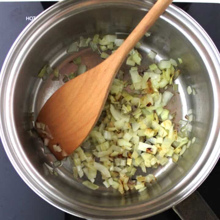 translucent, slightly browned chopped onion in saucepan with wooden spatula