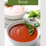 two white bowls of gluten free tomato soup garnished with basil