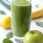 green smoothie in glass surrounded by green apple, banana, lemon, cucumber, and spinach leaves with title text