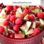 chopped apples, pears, fresh raspberries, kiwi, grapes, dried cranberries tossed together in a red bowl, with title text
