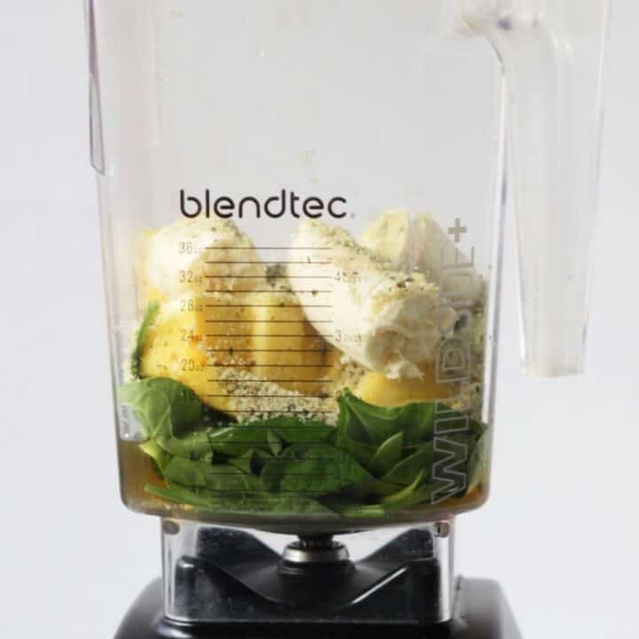 fresh spinach, pineapple chunks, and banana pieces layered into the jar of a Blendtec high-speed blender