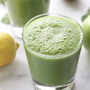 looking down toward the top of a glass of foamy green smoothie