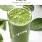 tall glass of green smoothie surrounded by spinach leaves, with title text