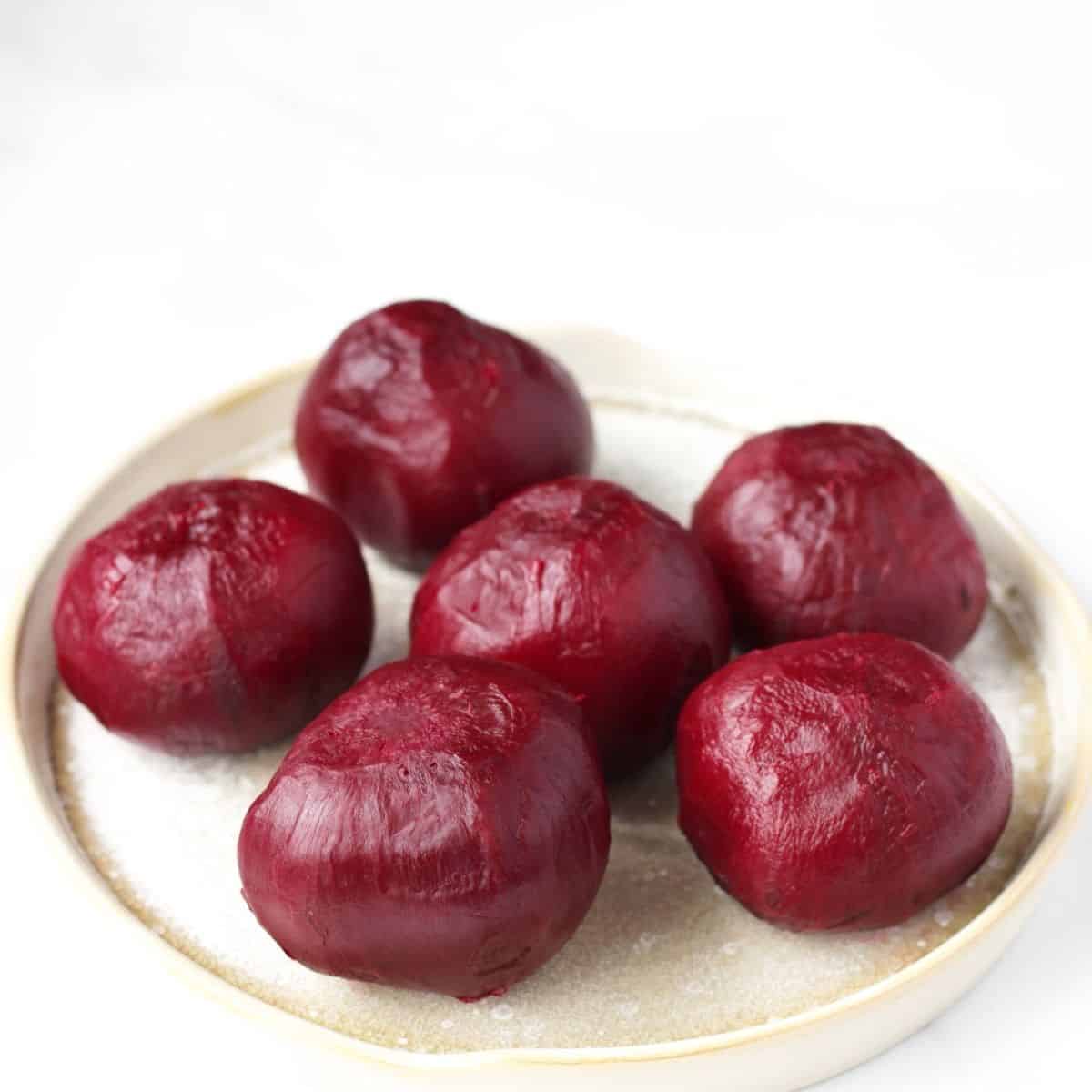 shiny, peeled, whole cooked beets on a beige plate