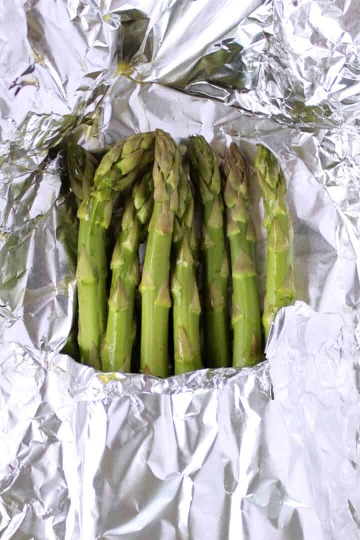 spears of grilled asparagus peeking out from a foil packet.