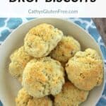 round, golden, gluten free drop biscuits piled onto an ivory plate.