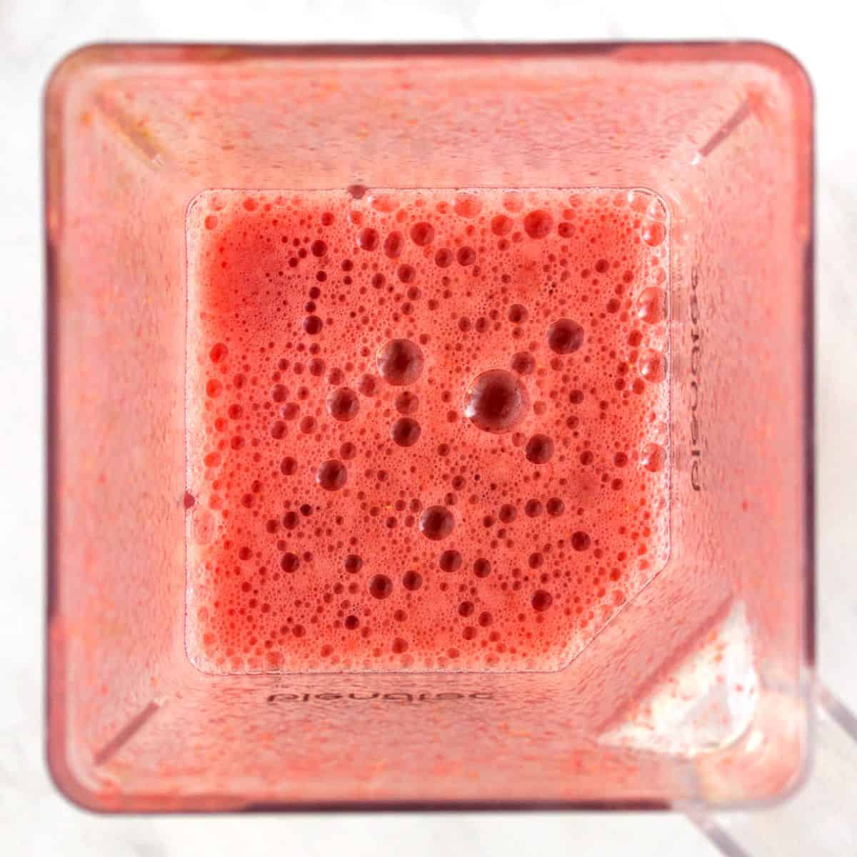 looking down into a pink, bubbly beverage in a blender jar.