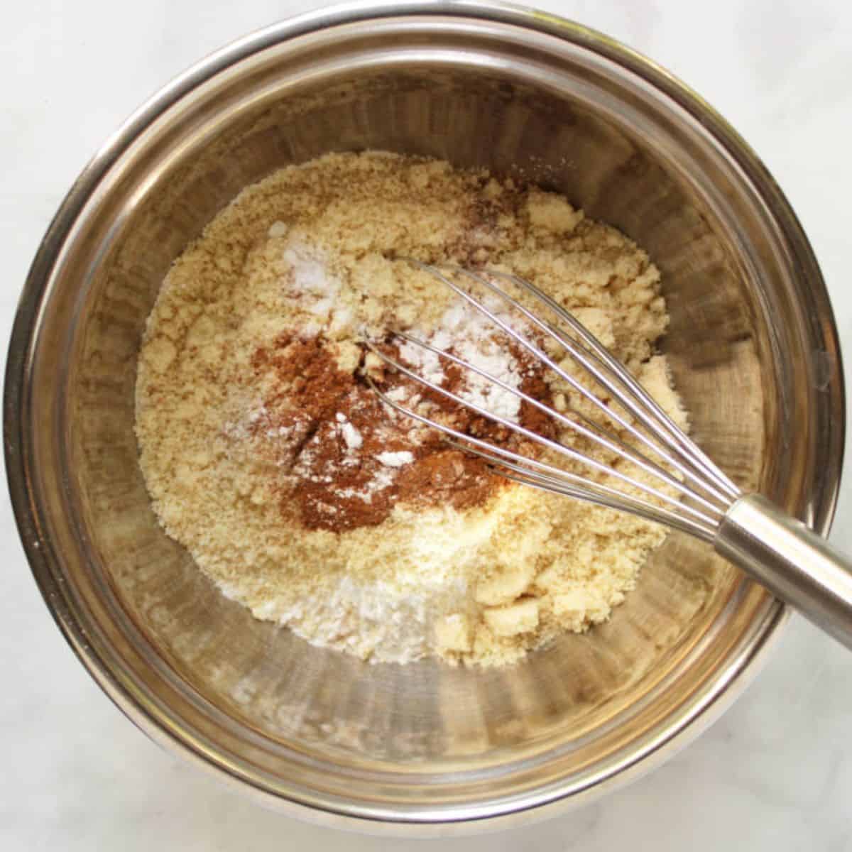 dry flours and spices in stainless steel mixing bowl with whisk.
