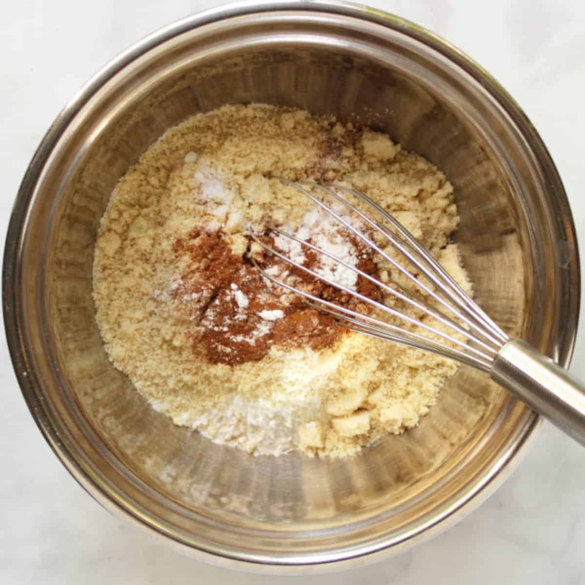 dry flours and spices in stainless steel mixing bowl with whisk.