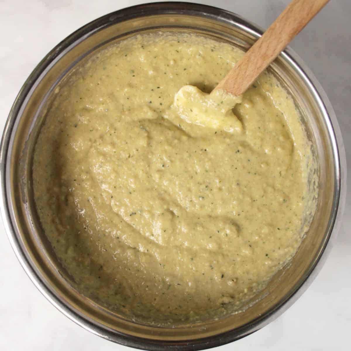 spatula with wooden handle in moist batter in mixing bowl.