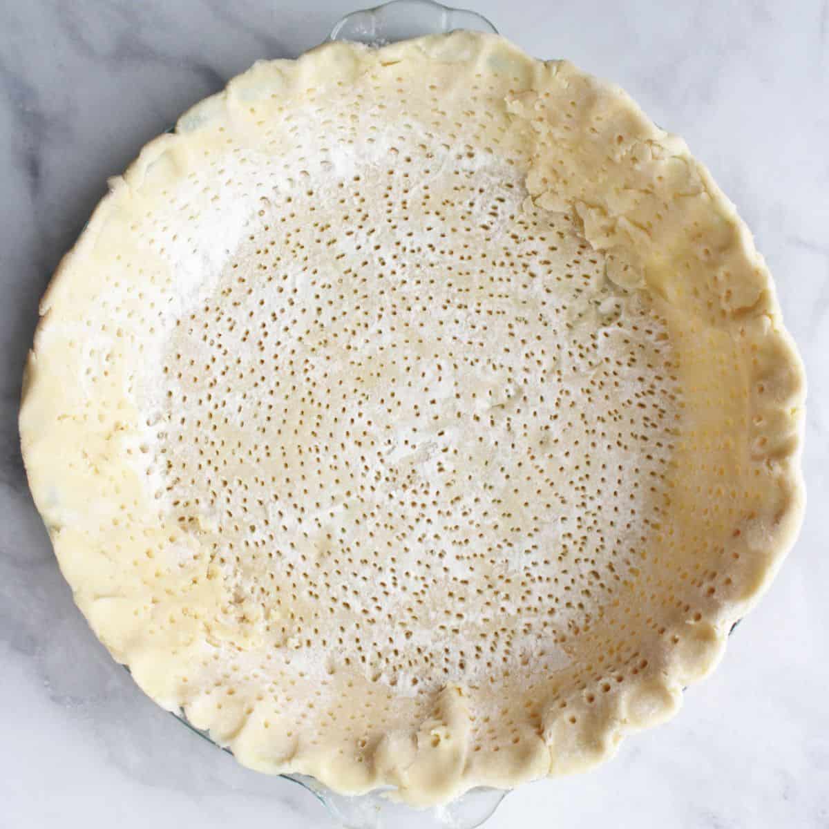 looking down into an unbaked pie crust poked full of tiny holes.