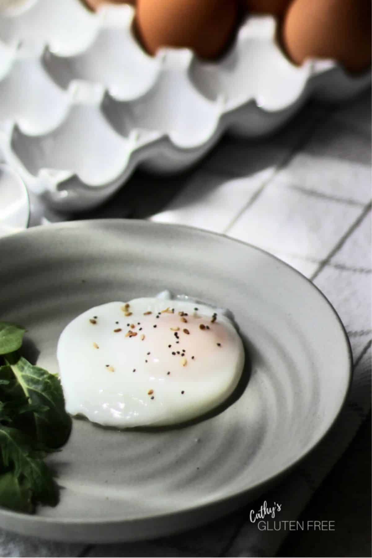 poached egg on a plate sitting on checkered cloth with fresh eggs behind