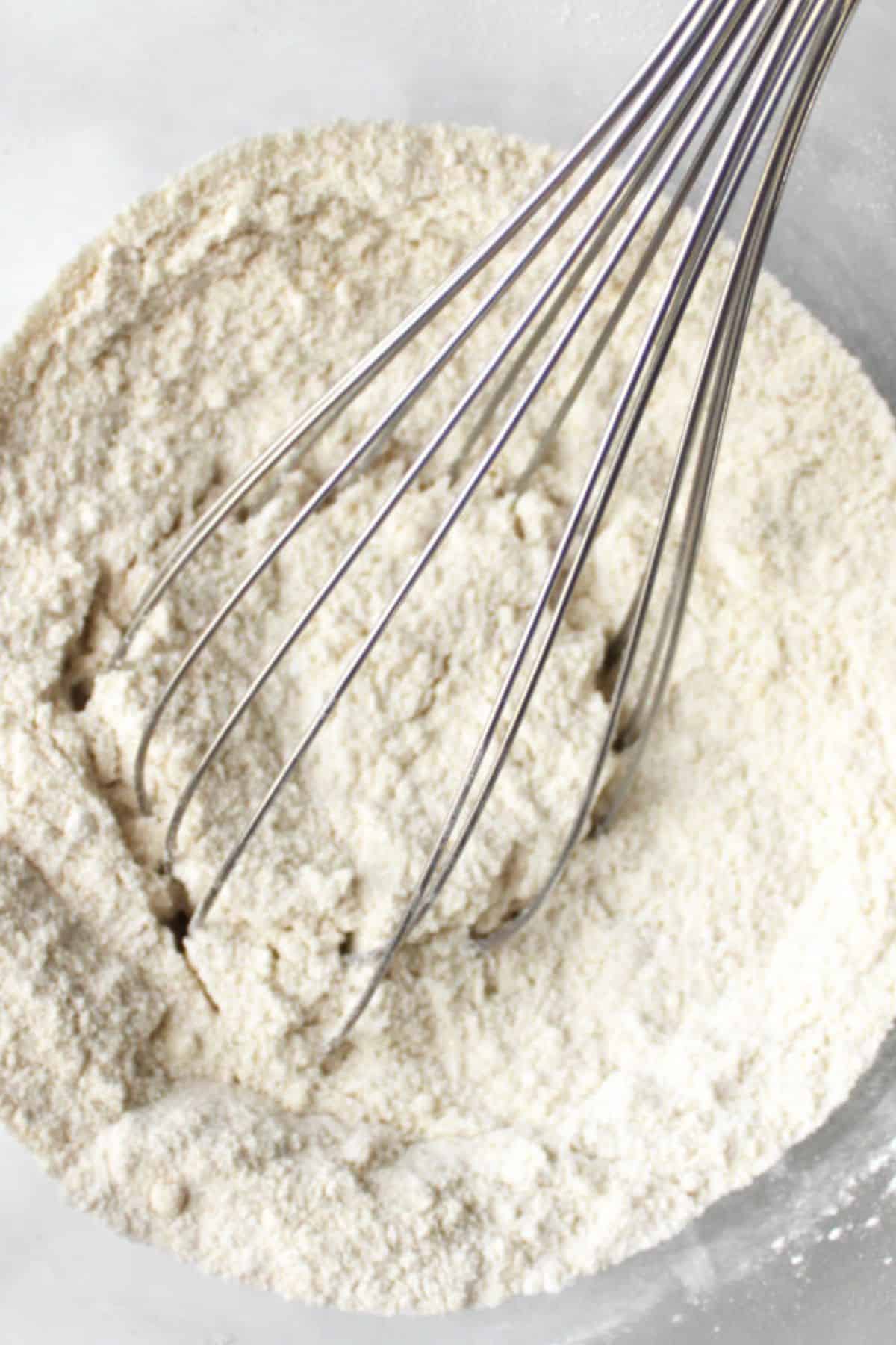 sorghum flour in a round bowl with a wire whisk in it.