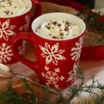 chocolate shavings sprinkled over whipped cream in red and white mug.
