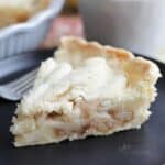 slice of pear pie with a top crust, sitting on black plate.