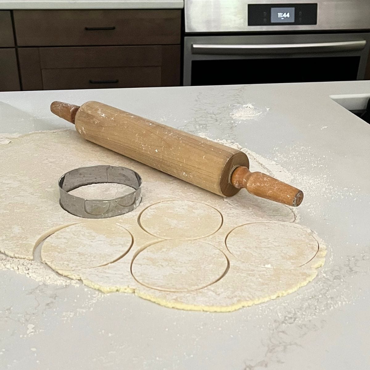 gluten-free dough rolled out on counter with rolling pin and circular cutter nearby.