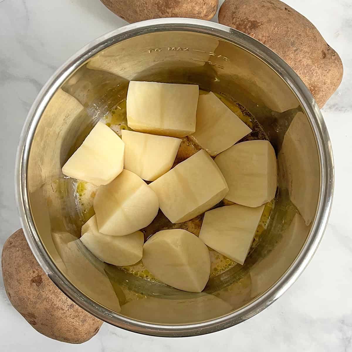 raw potatoes in large chunks in Instant Pot bowl.