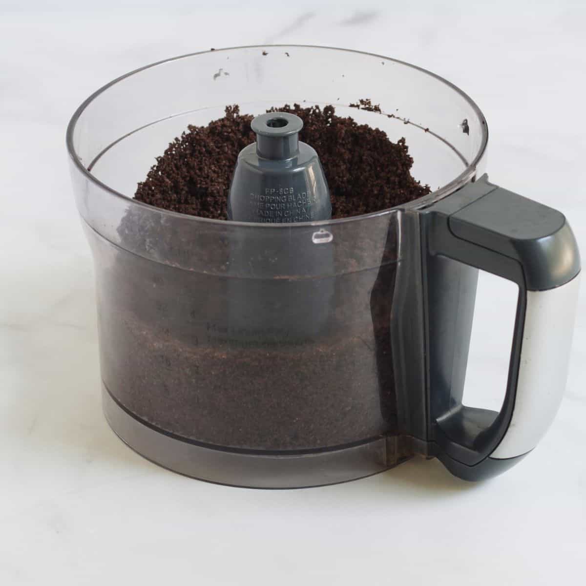chocolate cookie crumbs in food processor bowl.