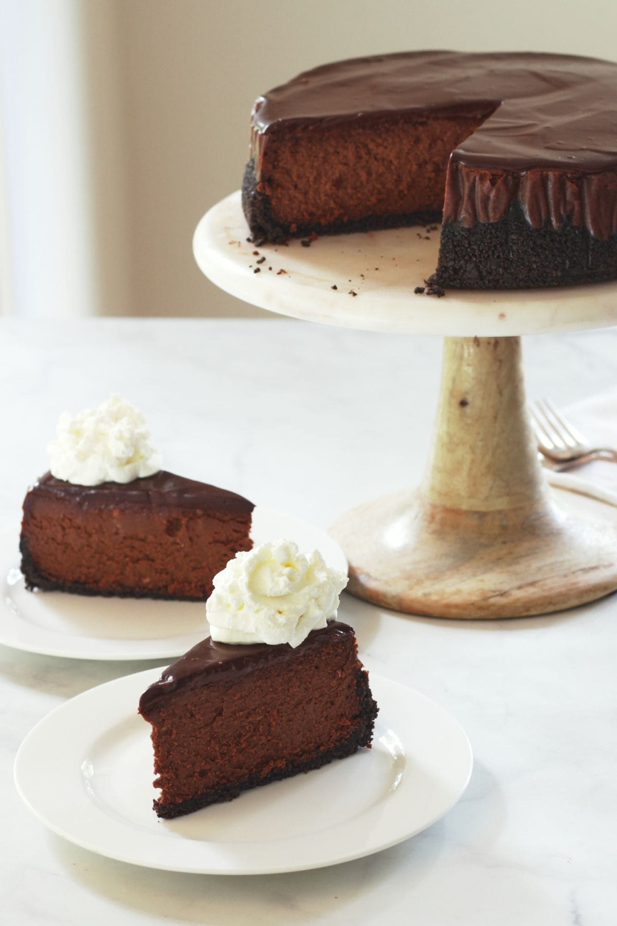two slices of chocolate cheesecake garnished with whipped cream.