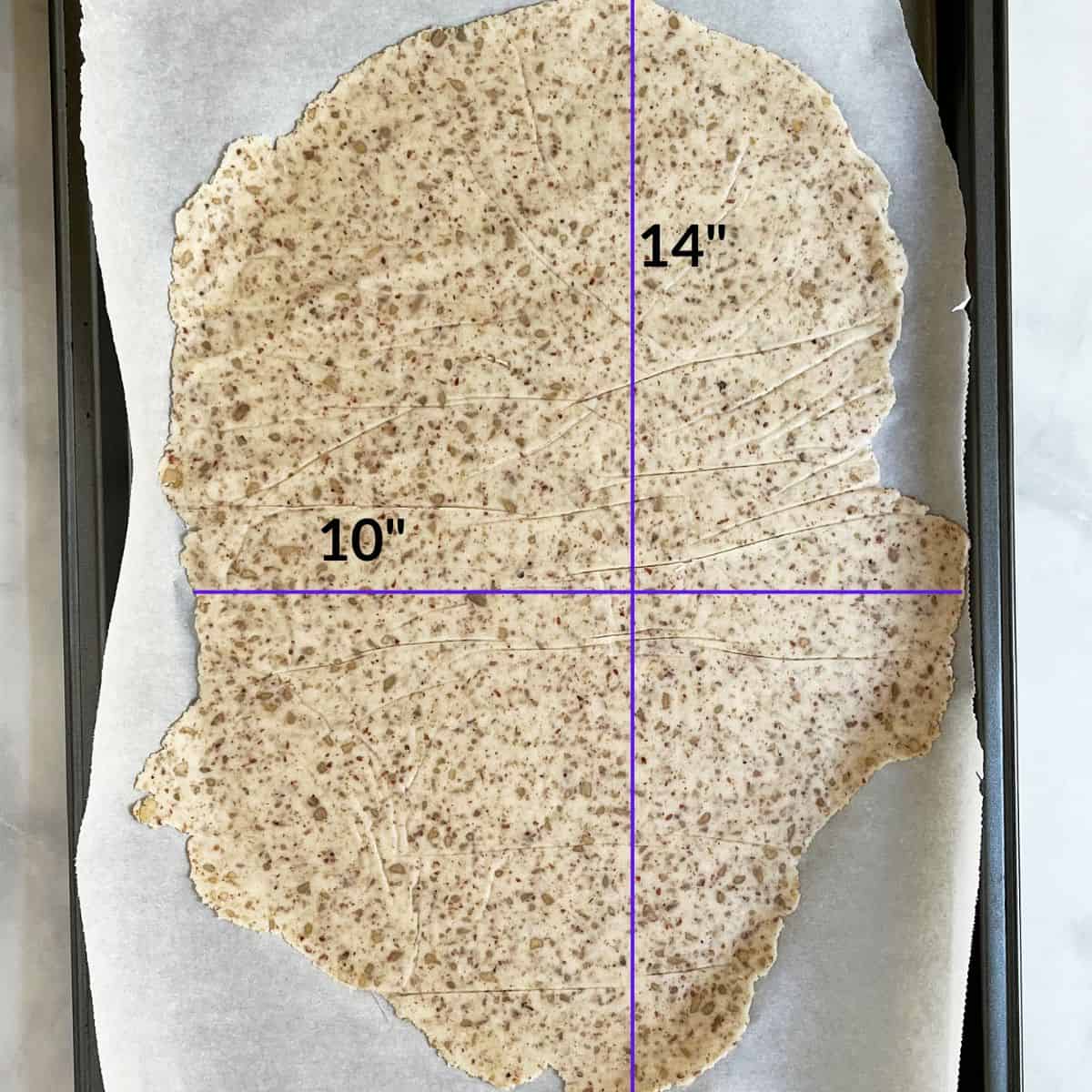 thinly rolled dough on parchment paper, labeled 10- by 14-inches.