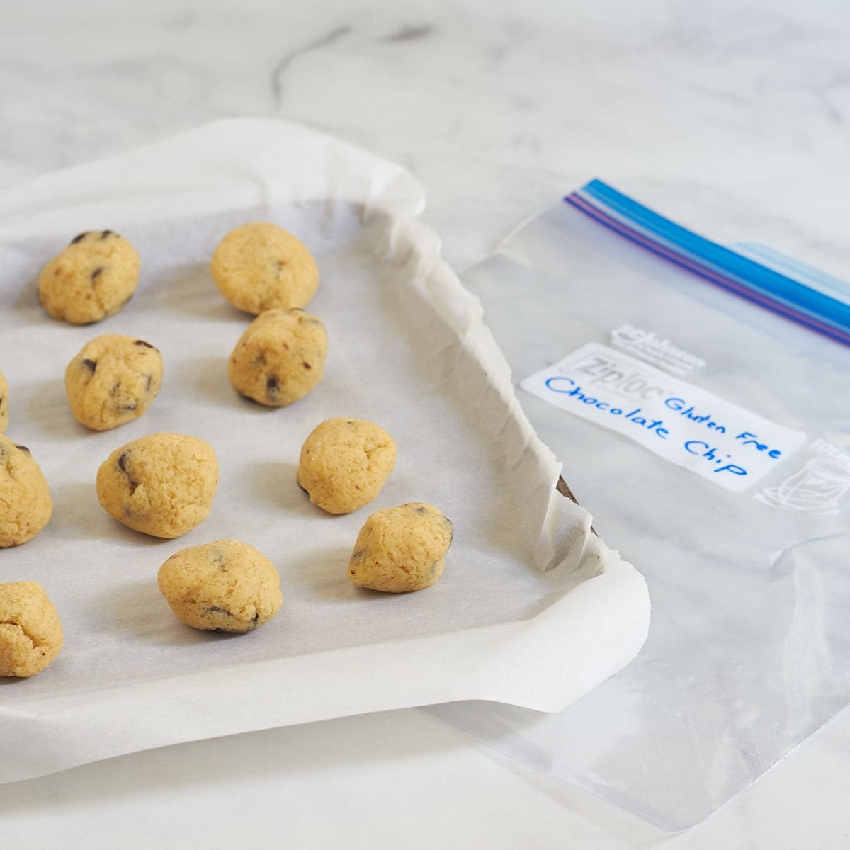 labeled freezer bag next to a tray of unbaked cookies.