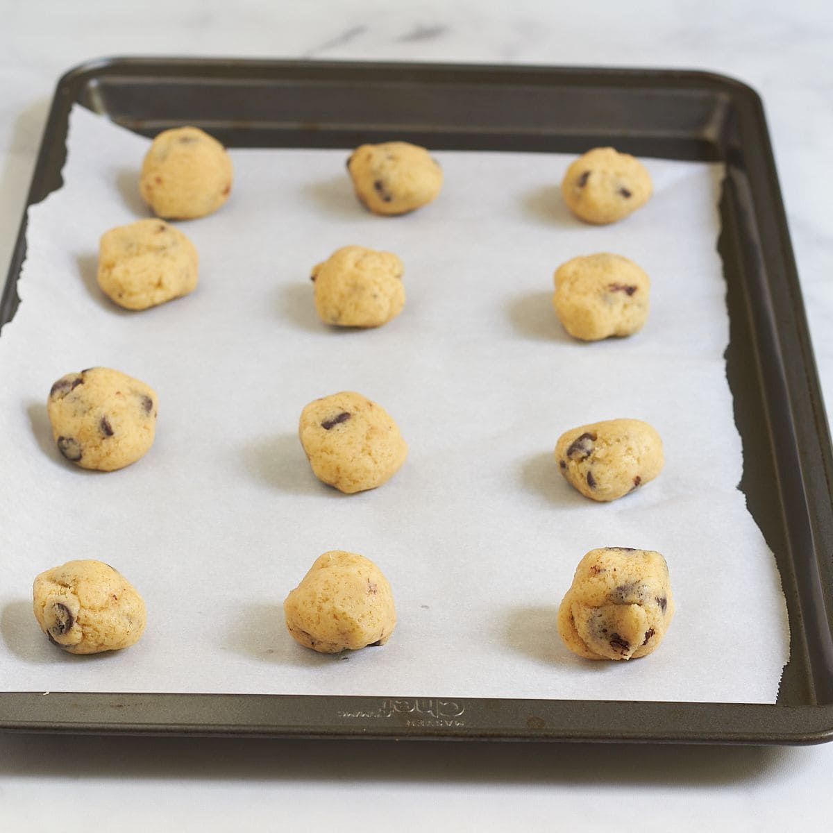 balls of cookie dough on a parchment-lined pan.