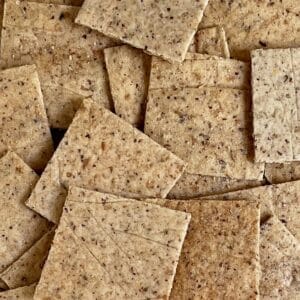 closeup, flat lay of square, golden, seedy crackers.