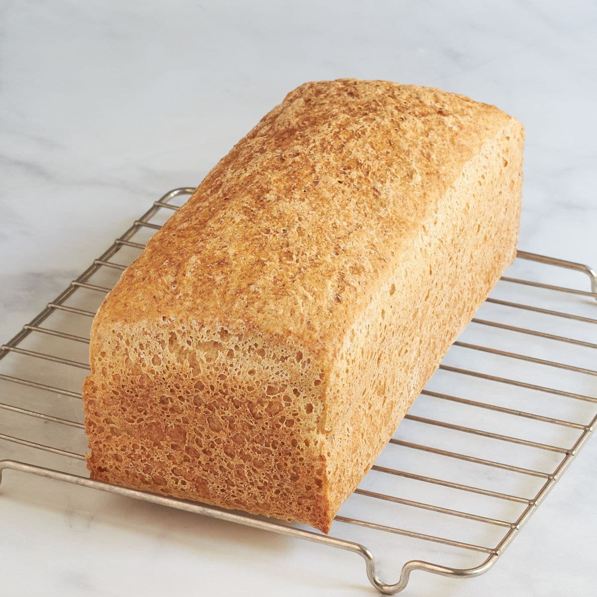 baked loaf of golden bread resting on a wire rack.