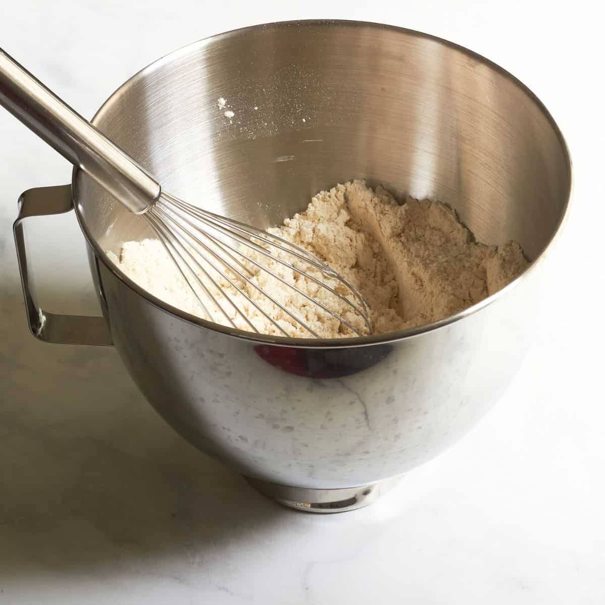 whisk resting in flour mixture in mixing bowl.