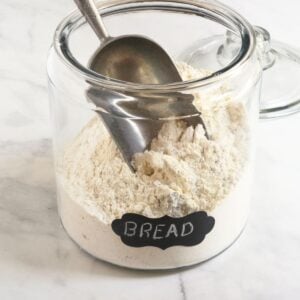glass canister of flour with a large scoop resting in it.