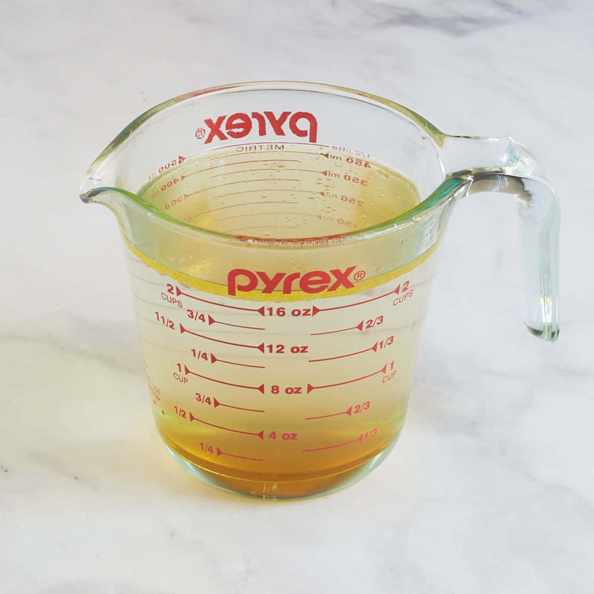 water, oil, honey, and vinegar in a Pyrex measuring cup.