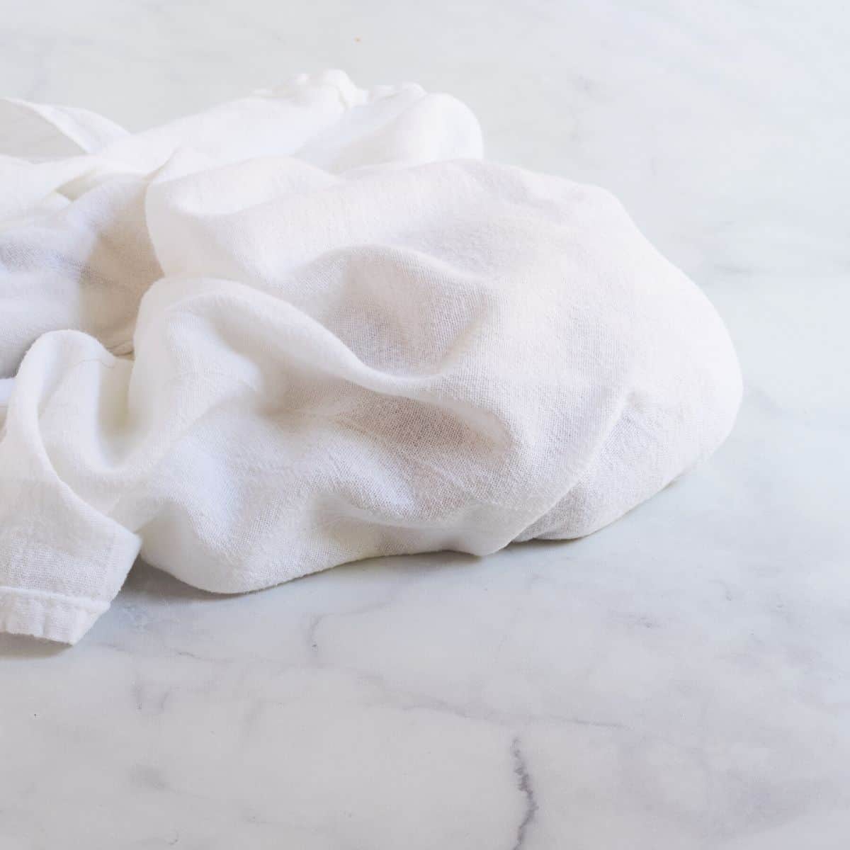 ball of dough wrapped loosely in a white tea towel.