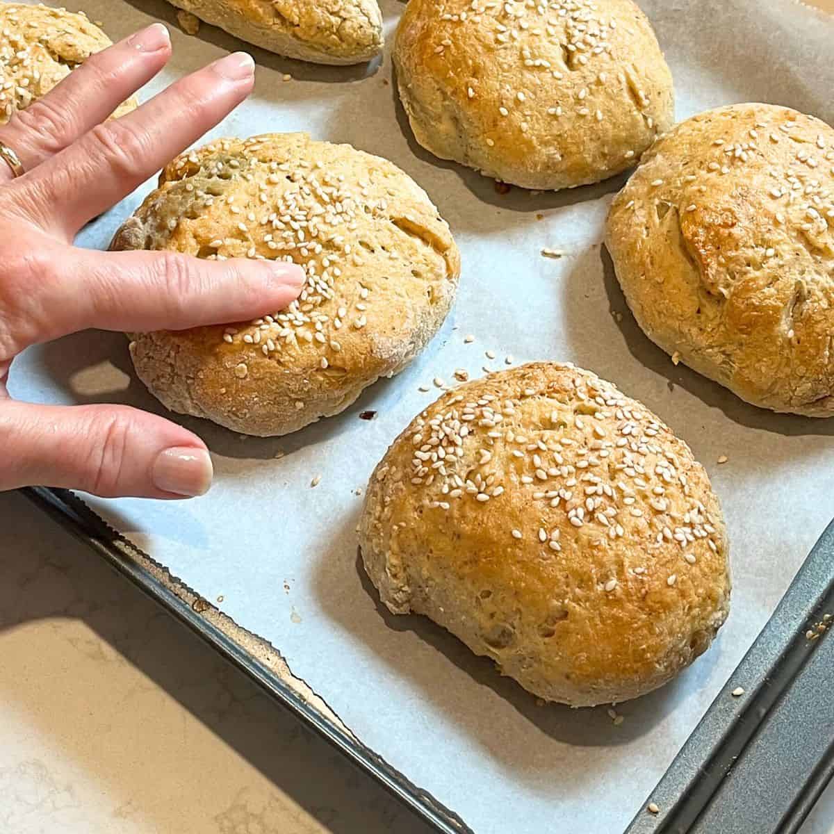 finger pressing a bun slightly to show softness.