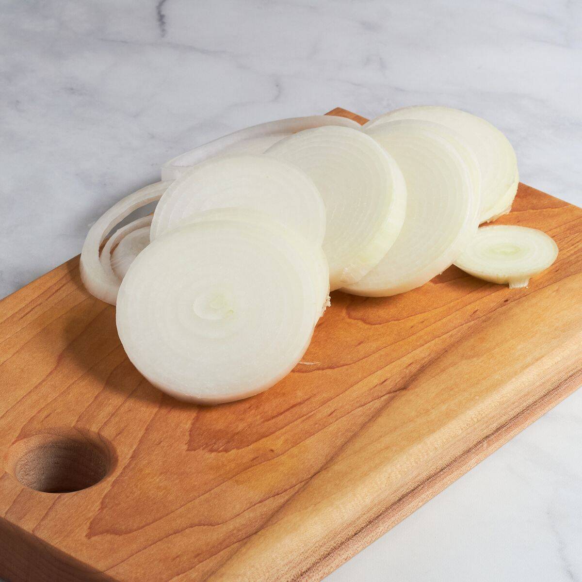 peeled, sliced onions on wooden board.