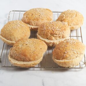 round, golden, sliced burger buns on rack.