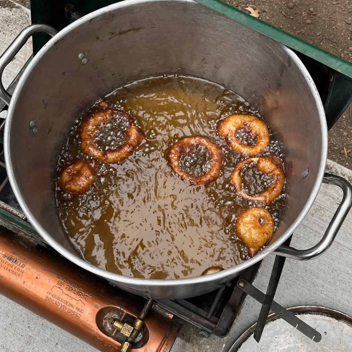 golden, battered onion rings browned in hot oil in large, deep pot.