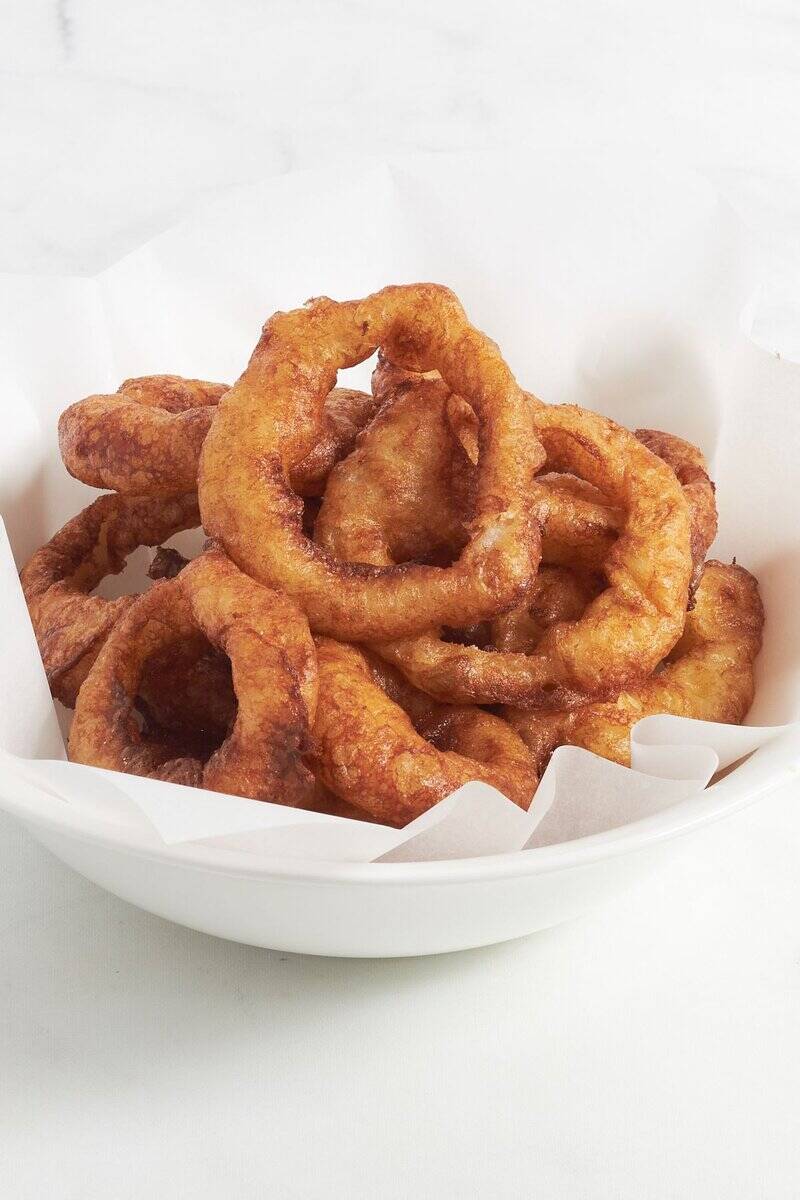 crispy, golden gluten-free onion rings in a white bowl in Cathy's Gluten-Free kitchen.