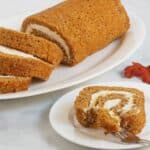 sliced pumpkin roll served on a white plate being eaten with a fork.