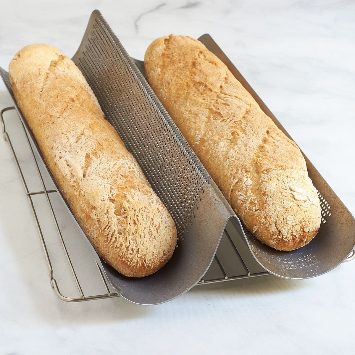 Fresh homemade gluten-free baguettes cooling on a wire rack.